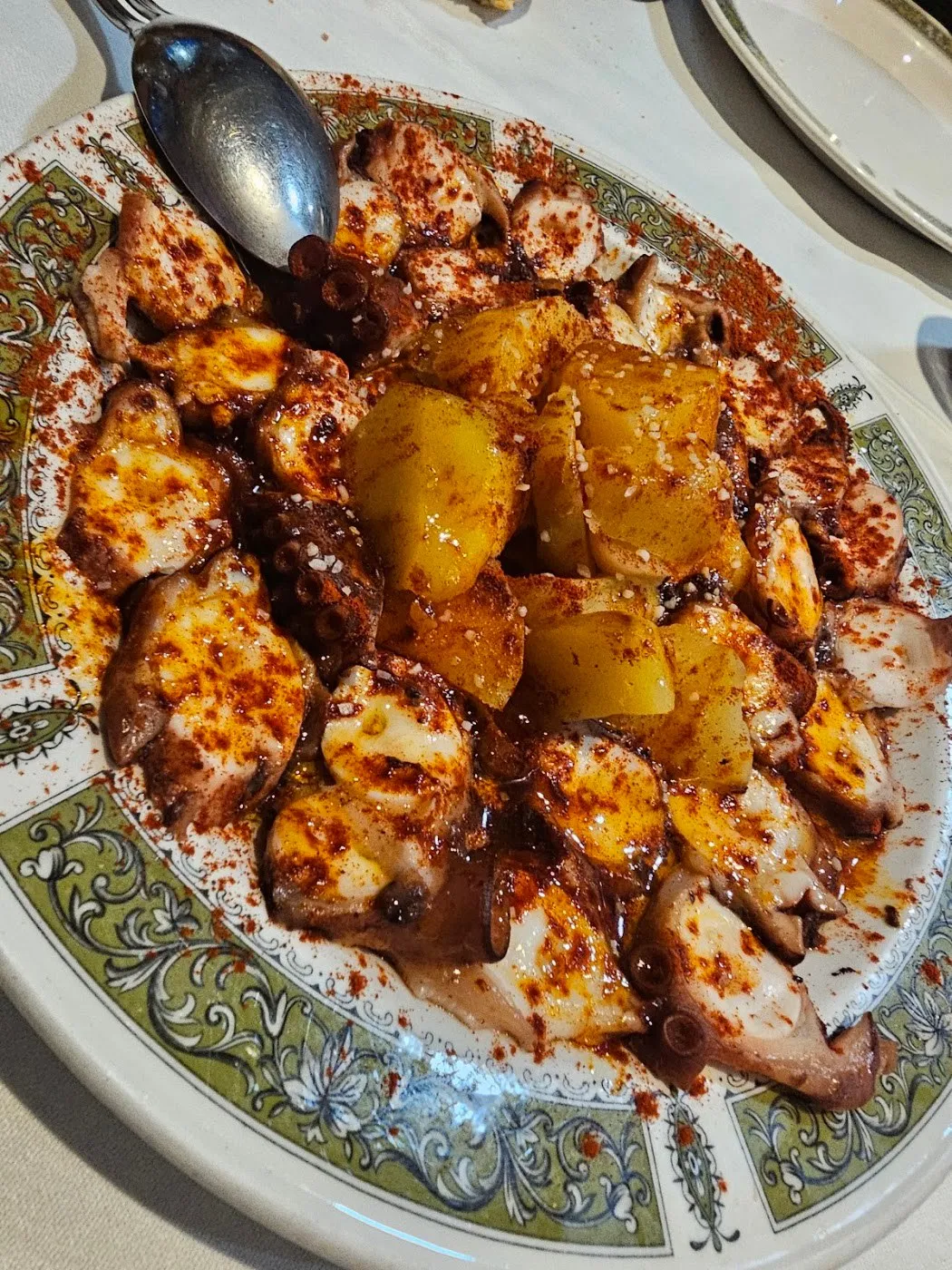 Pulpo con patata y pimentón en plato con orla verde