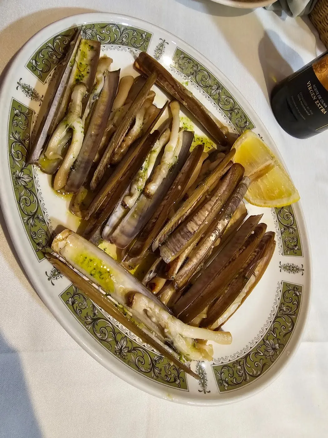 Navajas a la plancha con perejil y limón en fuente ovalada con orla verde