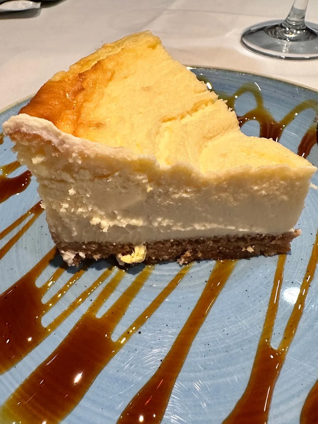 Porción de tarta de queso sobre plato azul con caramelo